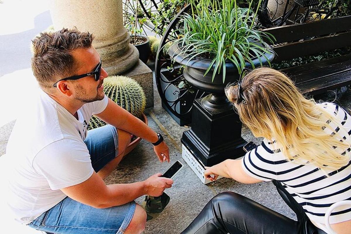 a man and a woman sitting on a bench looking at a cell phone