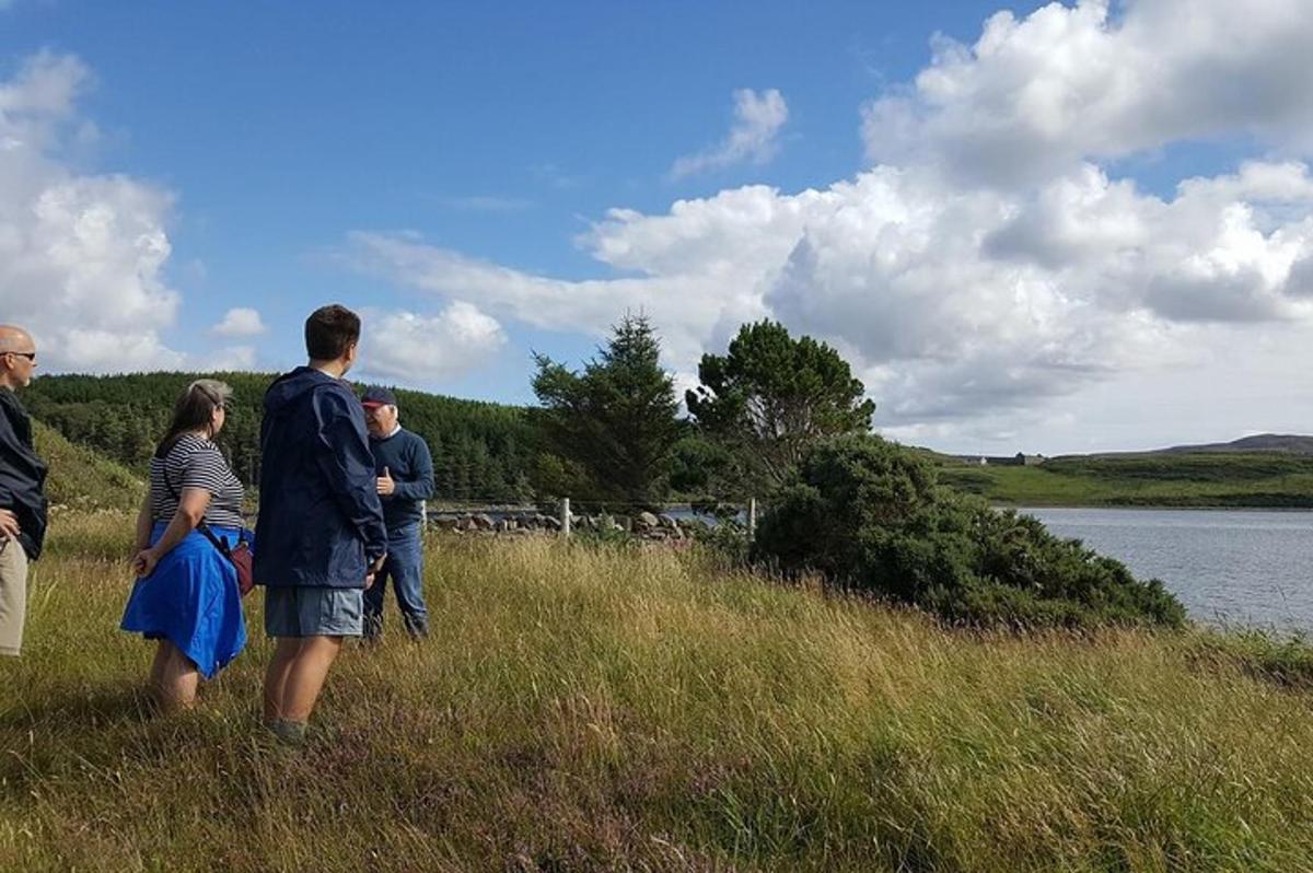 a group of people standing in the grass near a lake