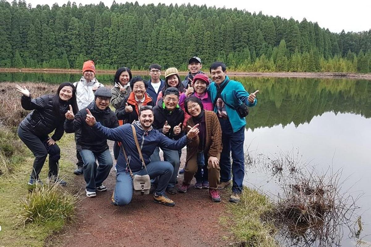 a group of people posing for a picture by a lake