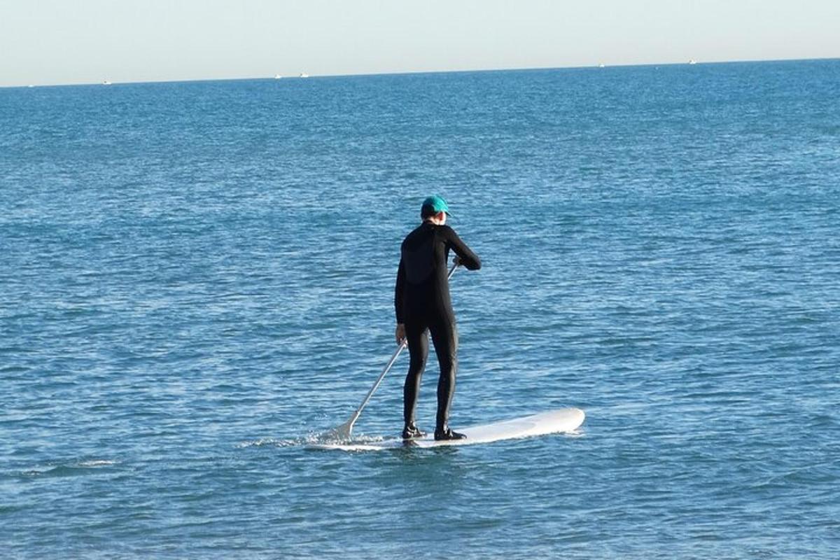 um homem em pé em uma prancha de remo no oceano