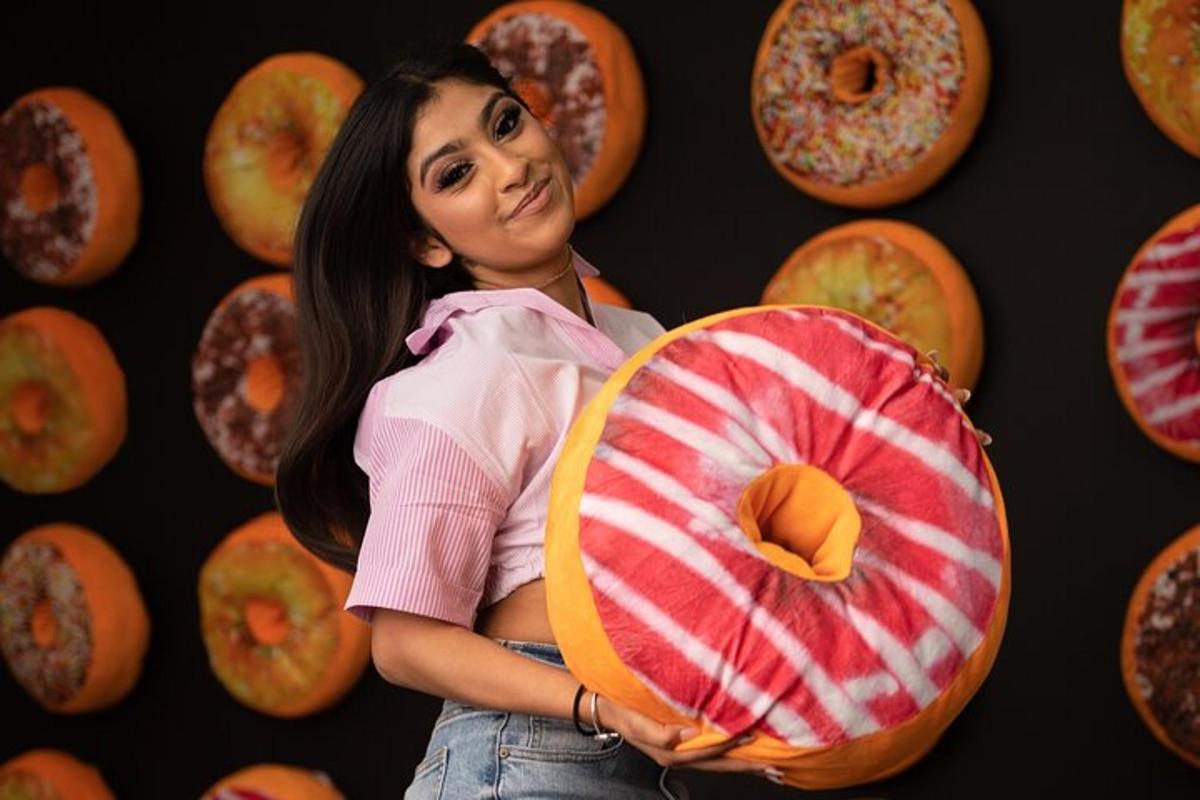 a woman holding a doughnut in front of a wall