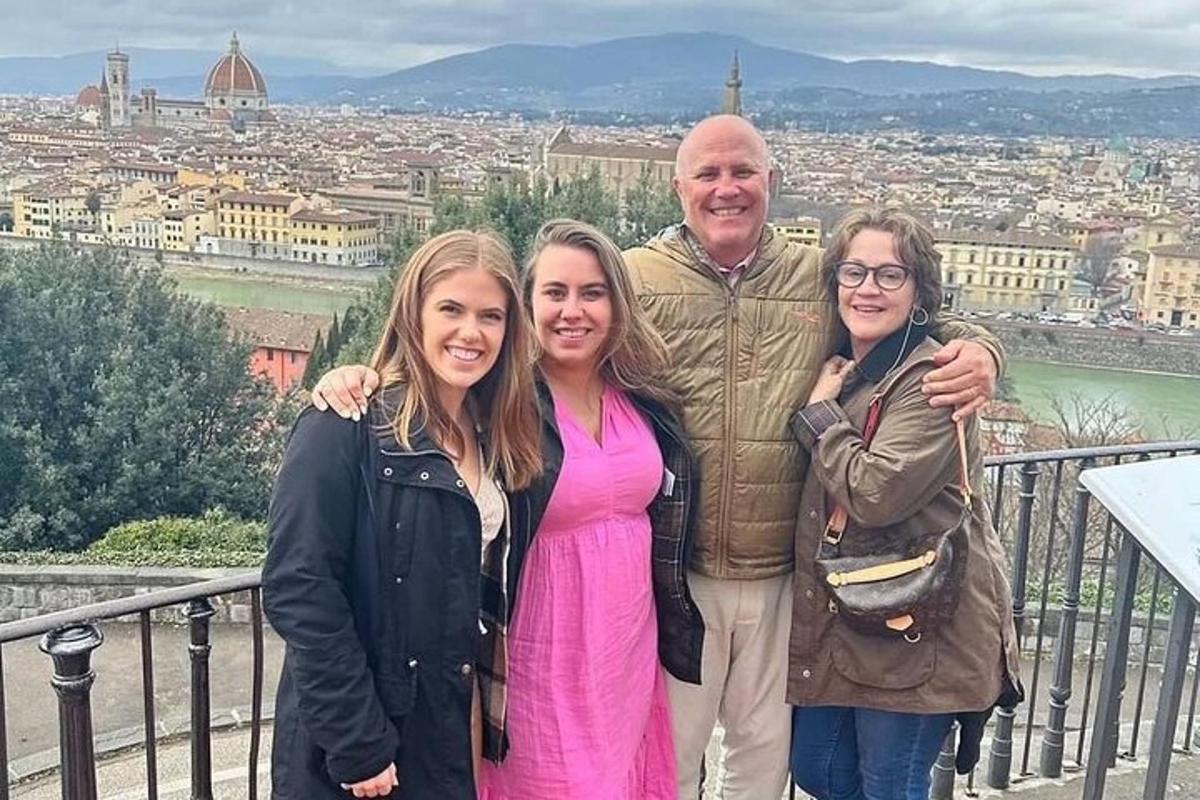 un uomo e tre ragazze in piedi su un balcone con una città