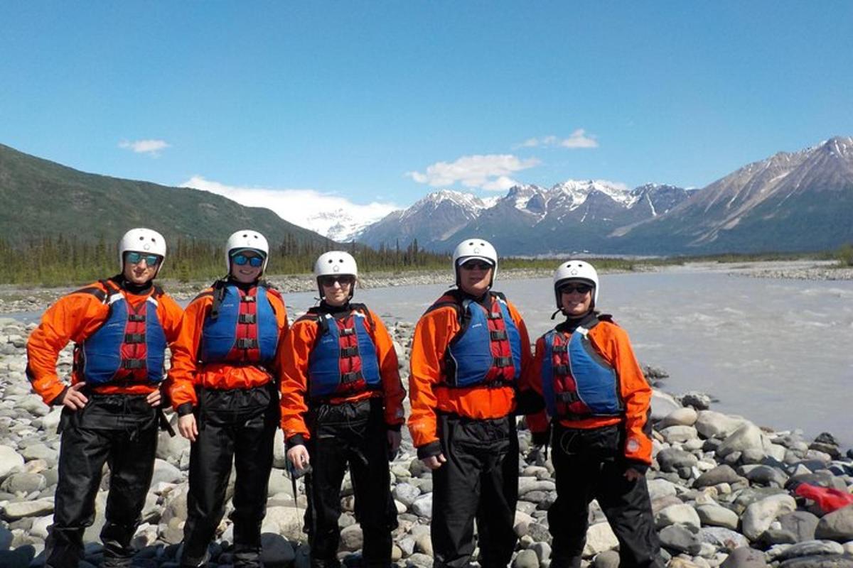 a group of men in orange jackets standing next to a river