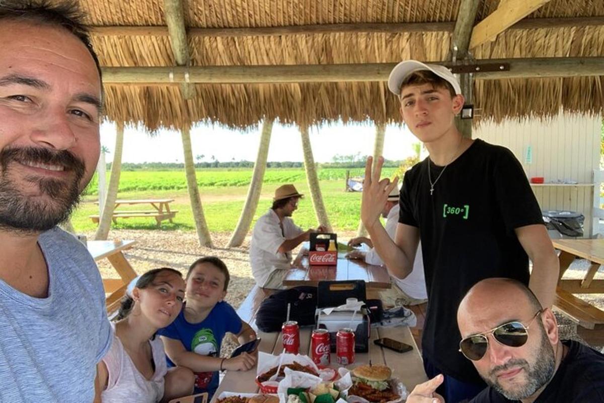 grupė žmonių, sėdinčių prie stalo su maistu