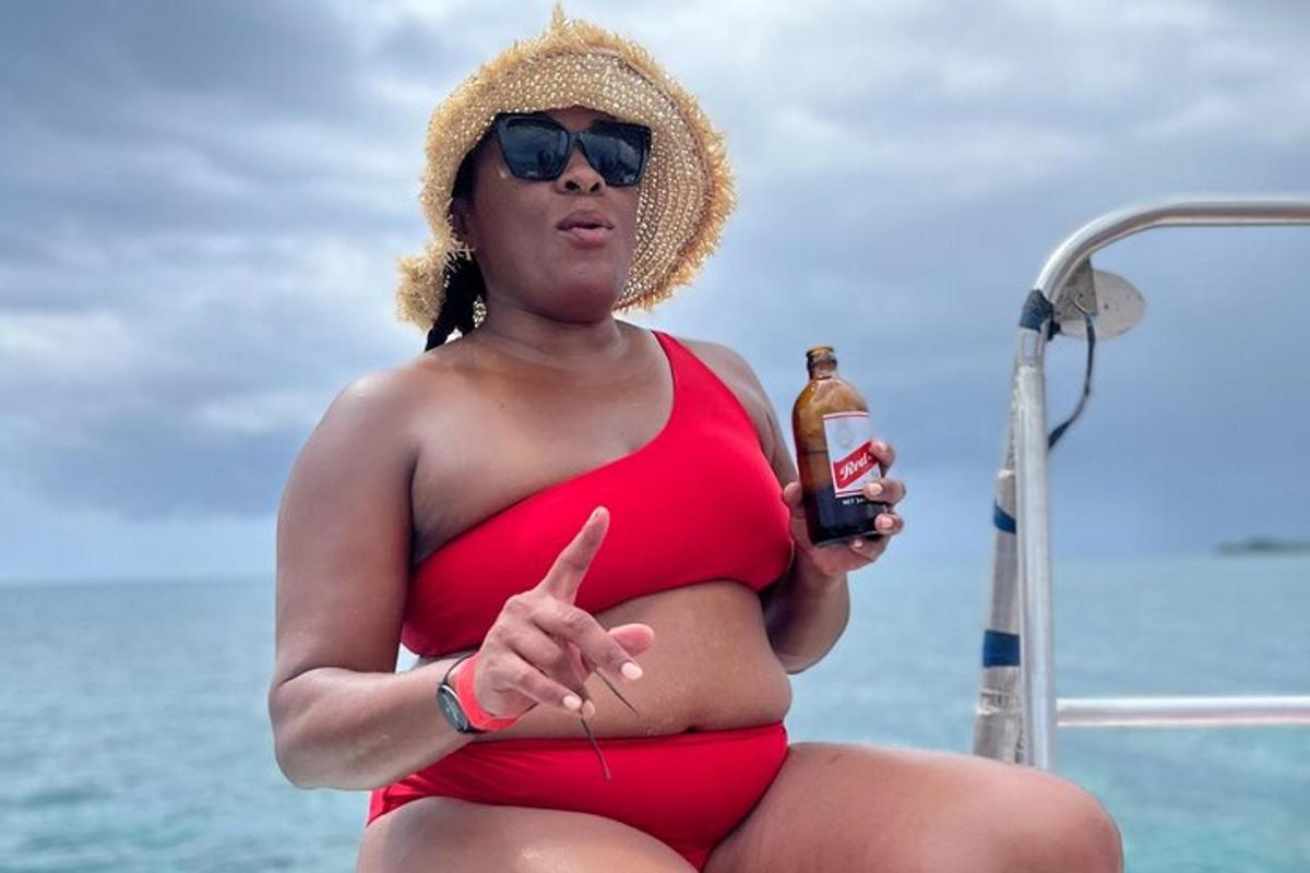 Una mujer embarazada en bikini rojo sosteniendo una botella de cerveza.