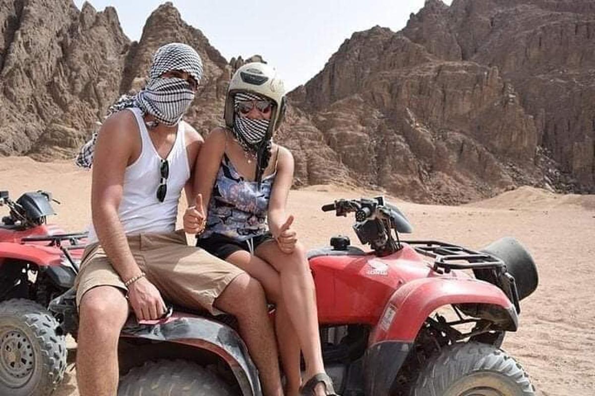 dues persones assegudes en un quad al desert