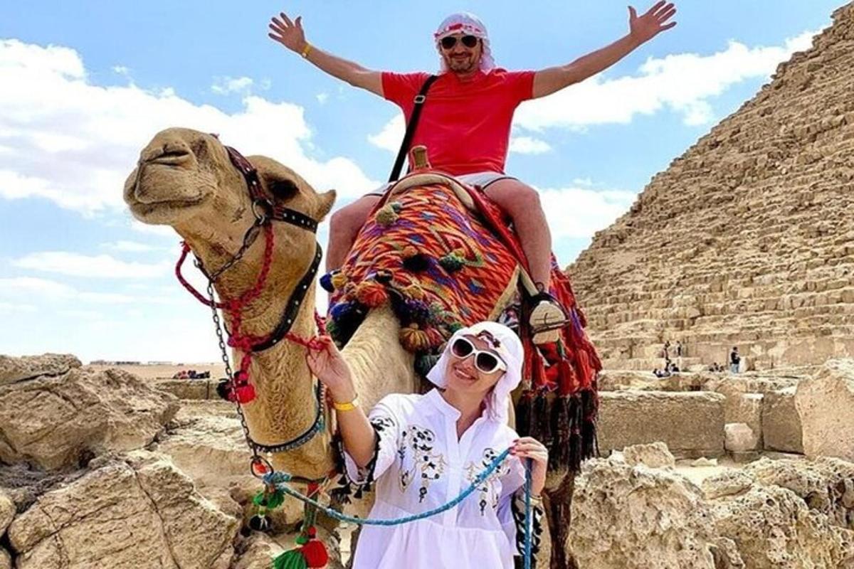 dvaja ľudia jazdiaci na chrbte ťavy pri pyramídach