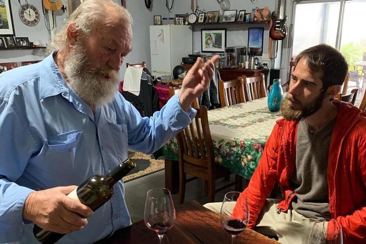 doi bărbați așezați la o masă cu o sticlă de vin