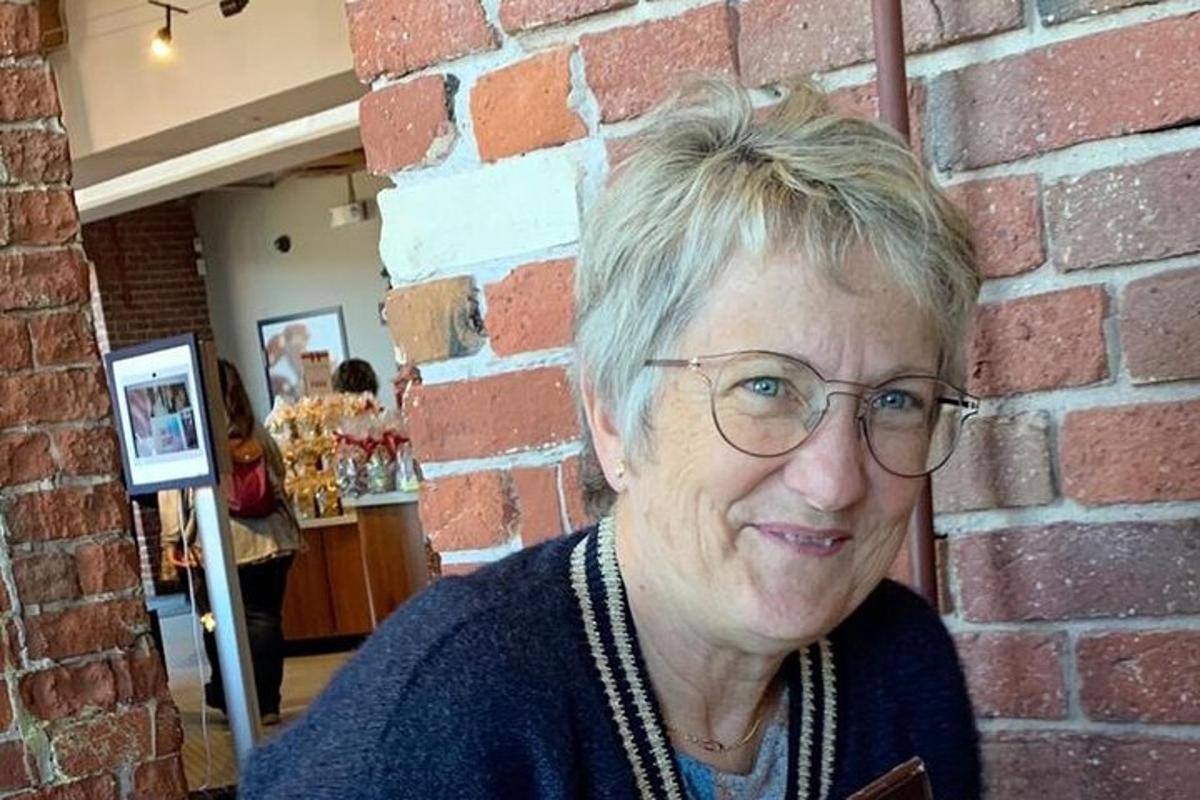 una donna con gli occhiali in piedi accanto a un muro di mattoni