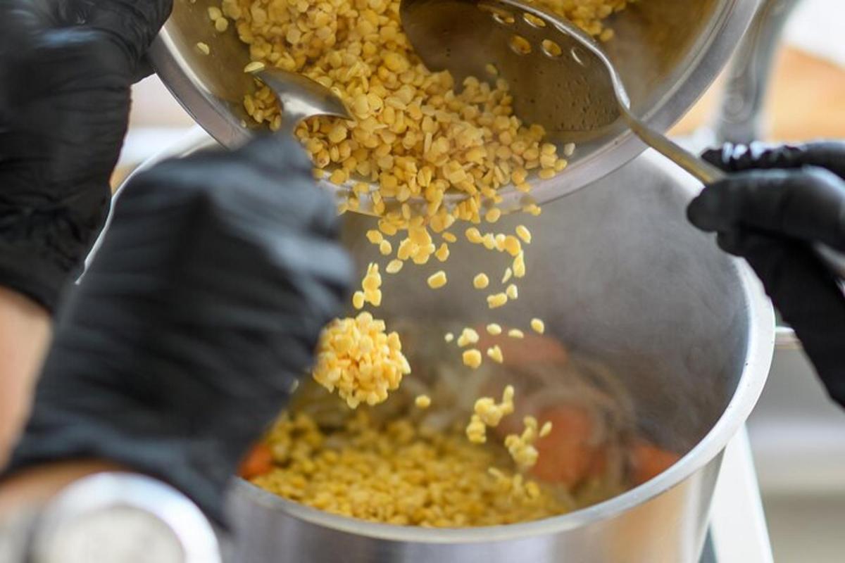 uma pessoa com luvas pretas segurando uma panela de comida