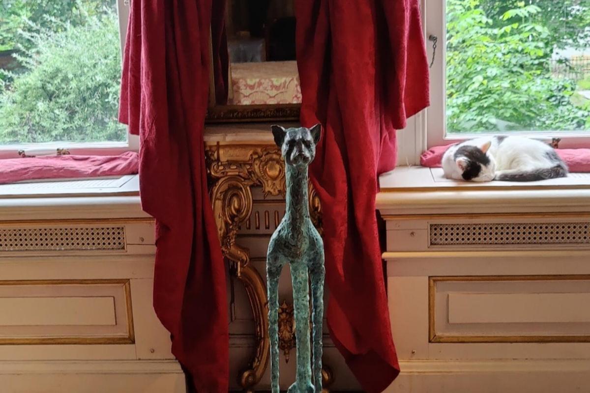 dos gats estirats a l'ampit d'una finestra i una estàtua de girafa