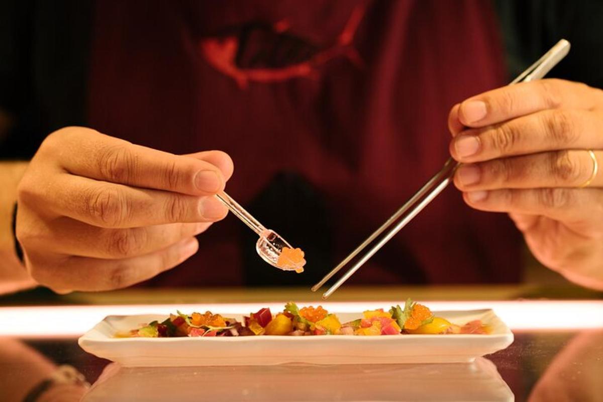 seseorang sedang makan sepinggan makanan dengan penyepit