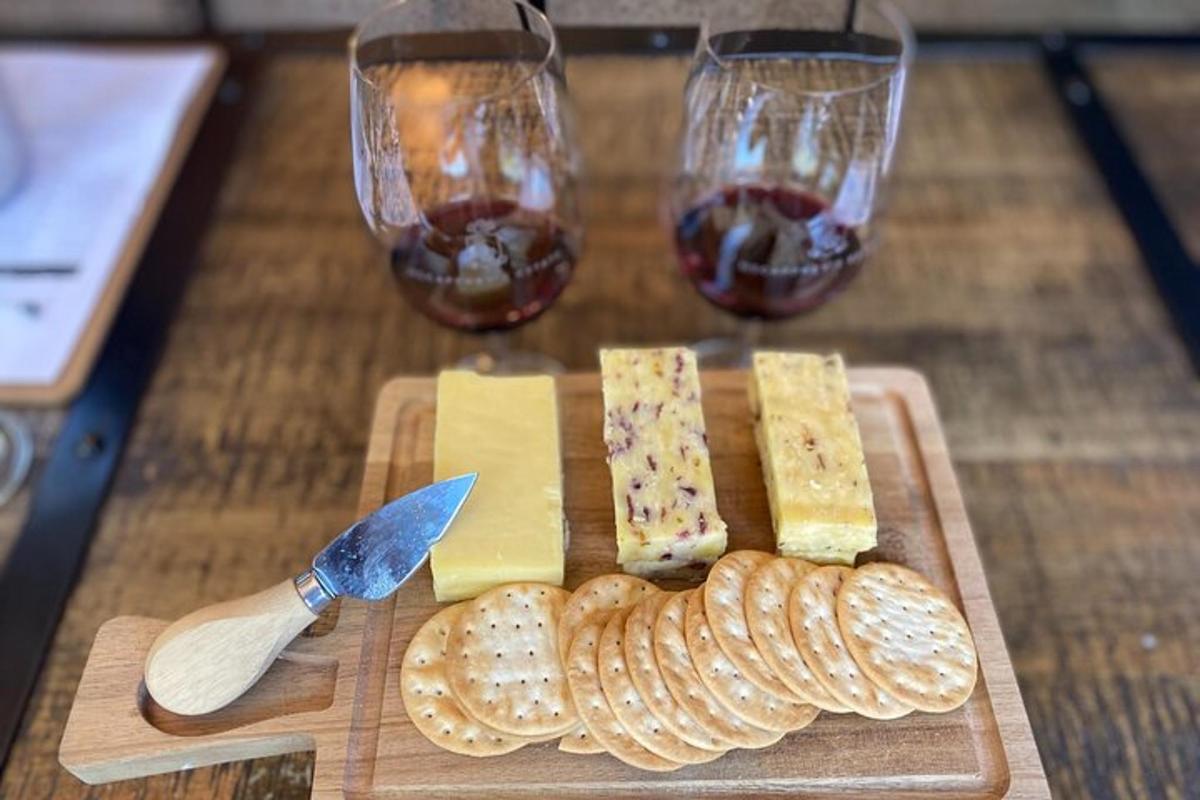 a cutting board with cheese and two glasses of wine