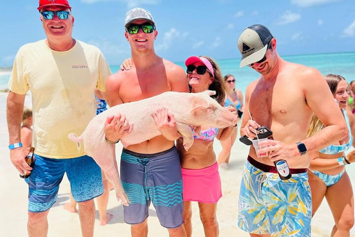 a group of men holding a pig on the beach