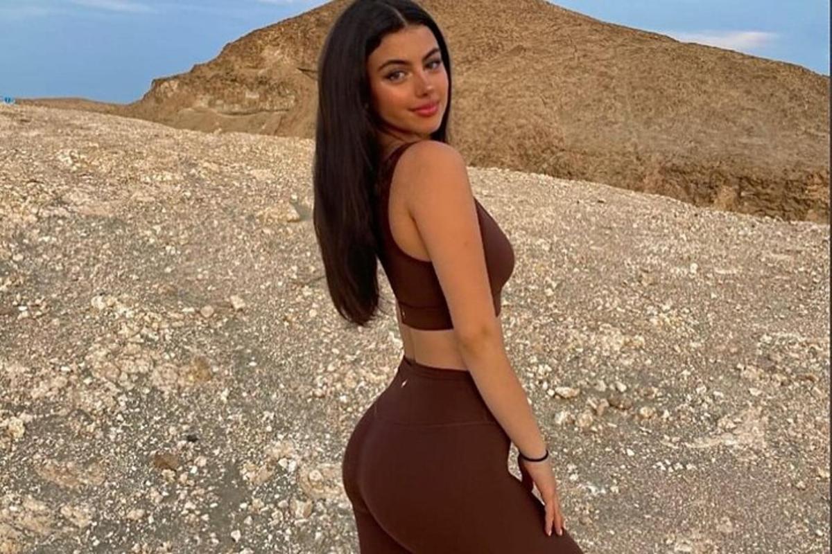 a woman in a brown dress standing on a rock