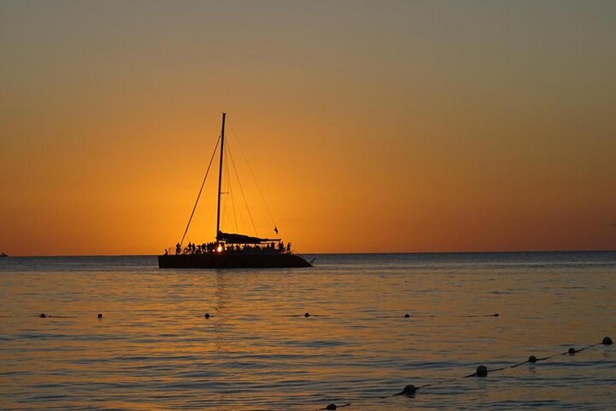 a boat in the ocean at sunset with people on it