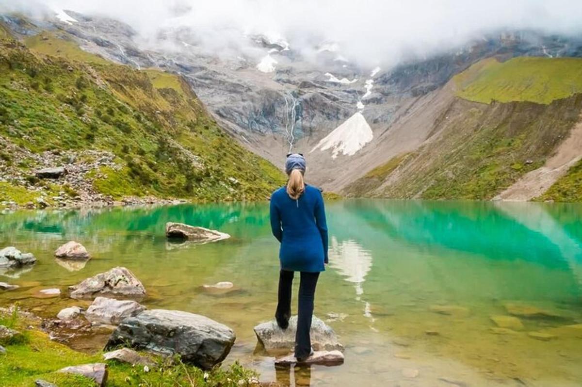una donna in piedi su una roccia in un lago di montagna