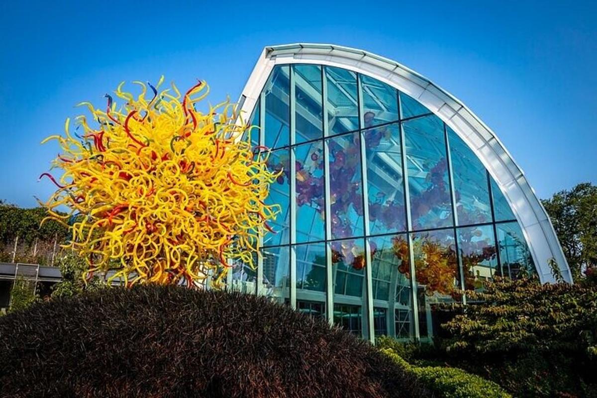 a glass building with a large yellow sculpture in front of it