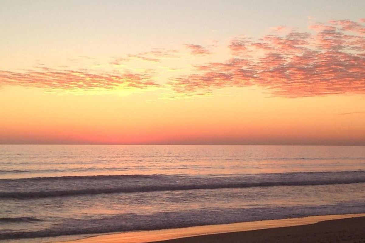 ein Sonnenuntergang an einem Strand mit Blick auf das Meer