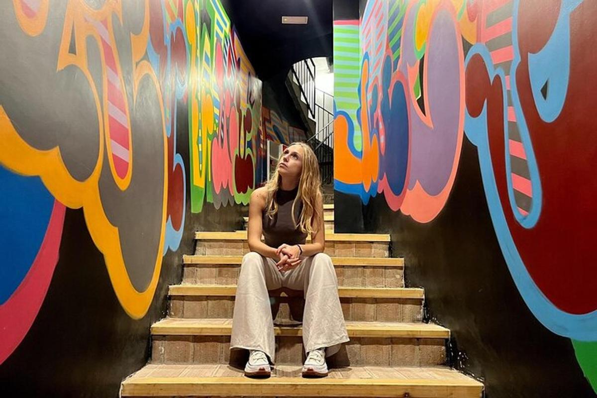 Una mujer sentada en las escaleras frente a una pared.
