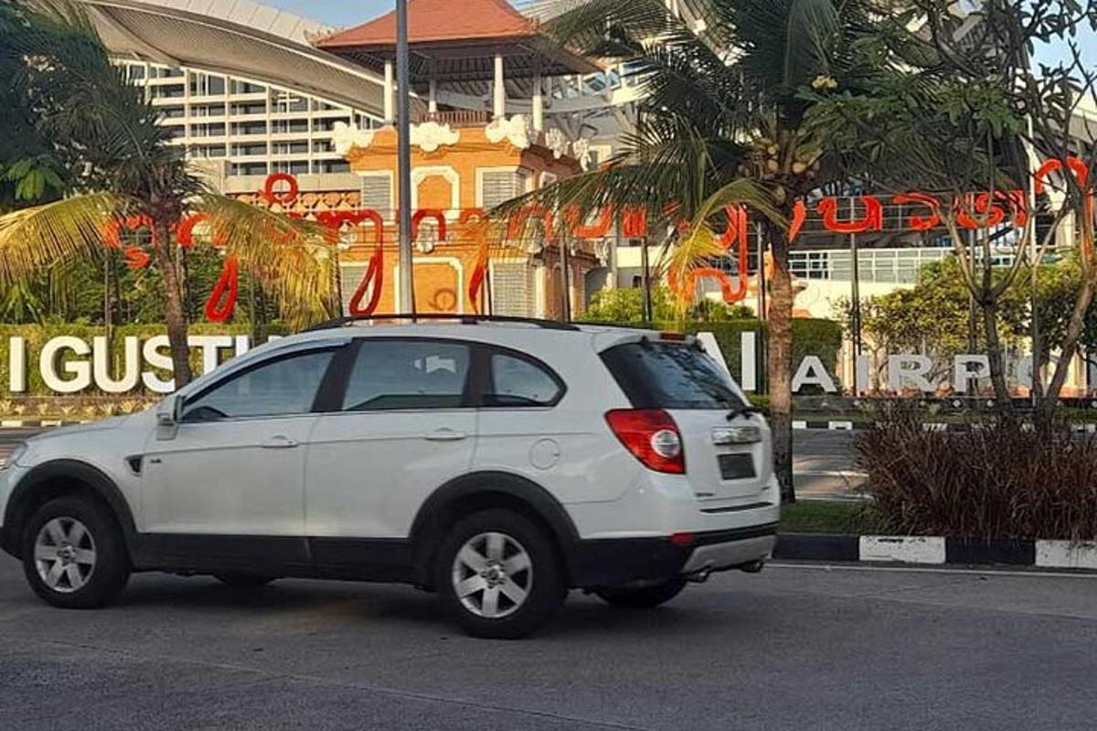 một chiếc xe màu trắng đỗ ở bãi đậu xe trước một tòa nhà