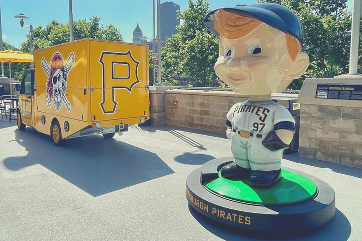 a statue of a baseball player standing next to a food truck