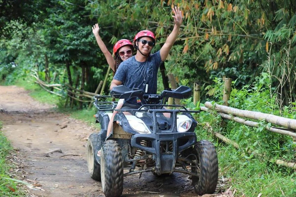 a man and woman riding on a four wheeler on a trail