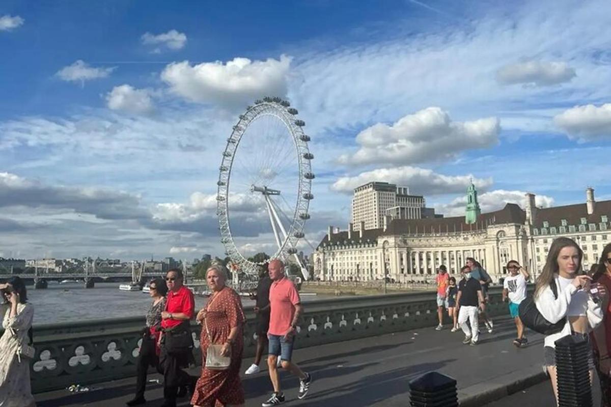 Skupina lidí stojících na mostě poblíž London Eye