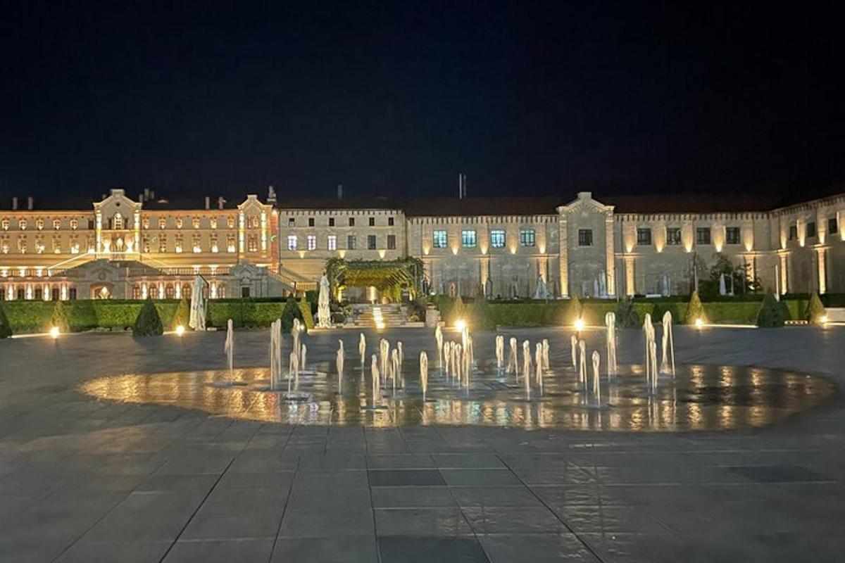 a fountain in front of a large building at night