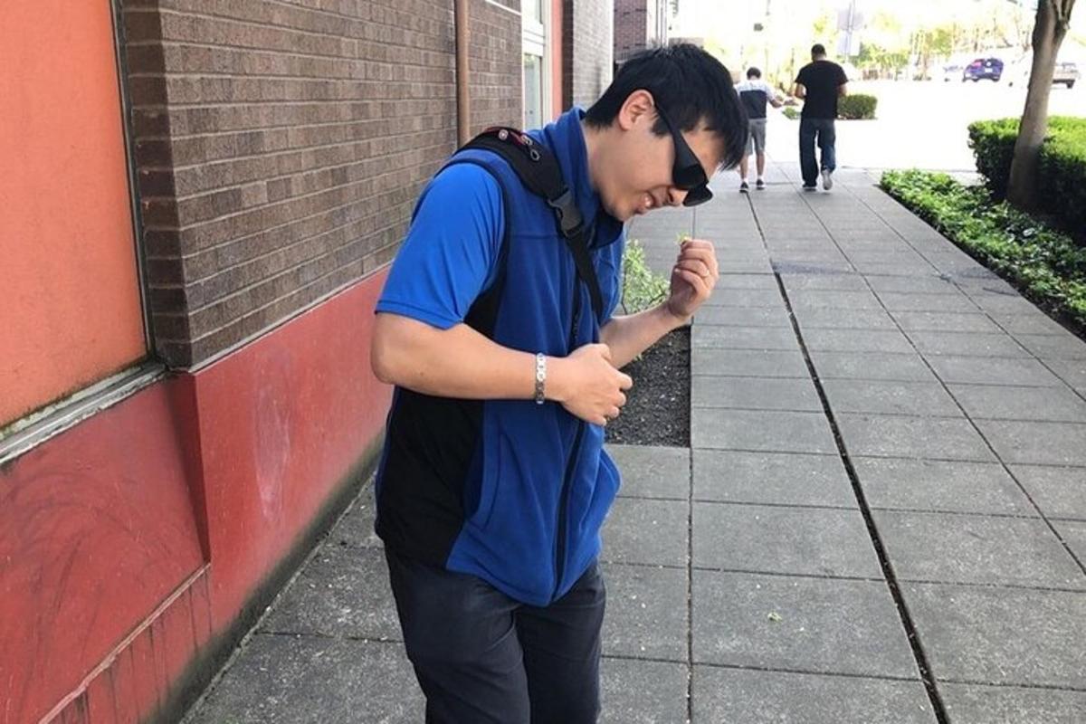 maður stendur á gangstétt og horfir á farsíma
