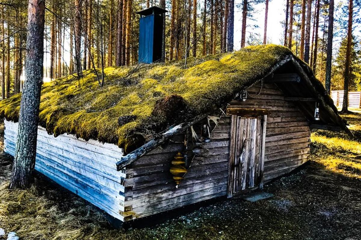 an old log cabin with a grass roof