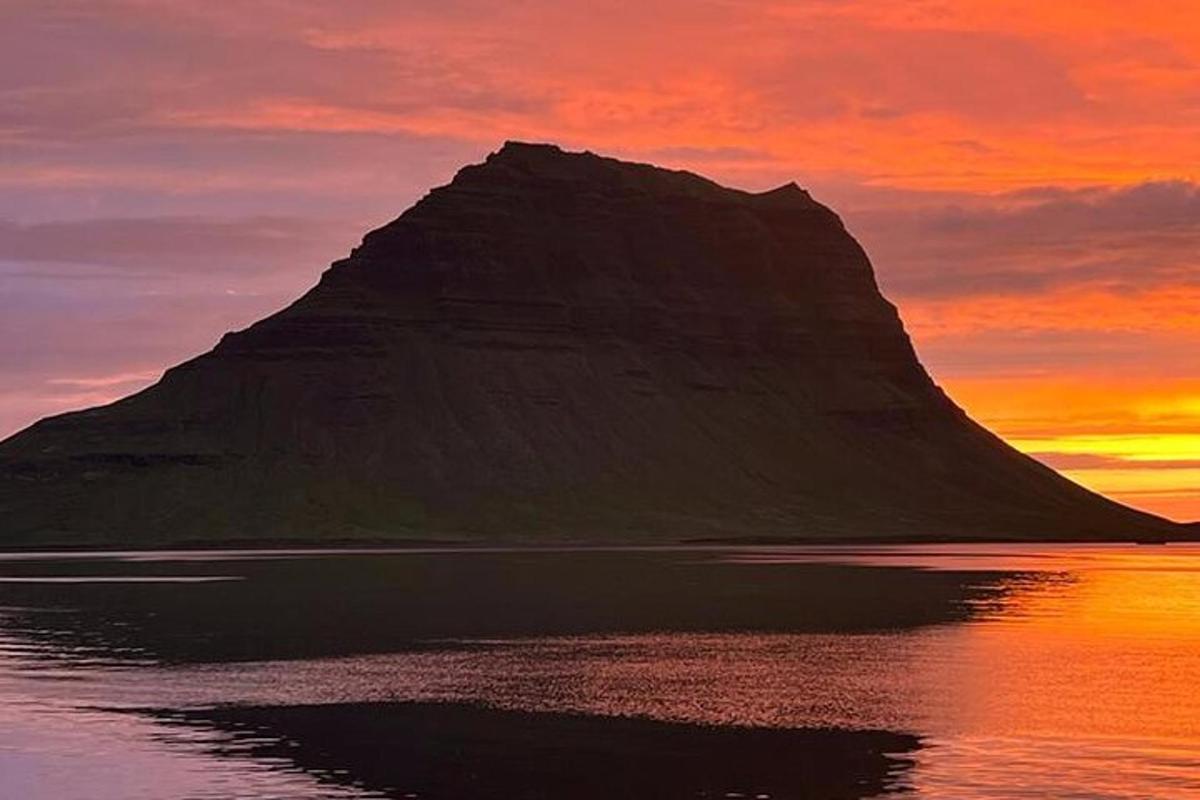 a mountain sitting in the water at sunset