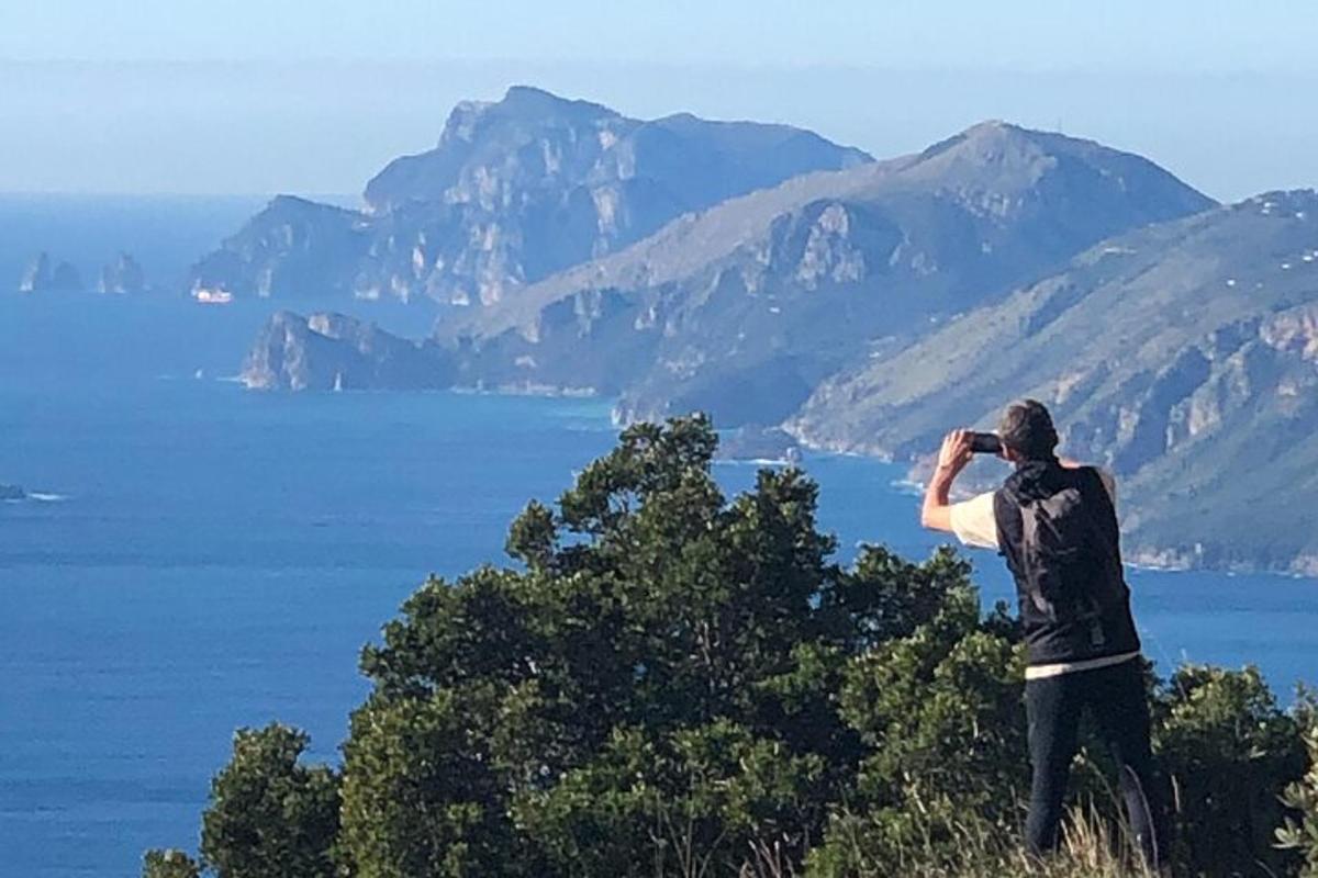 Un hombre tomando una fotografía del agua y las montañas.