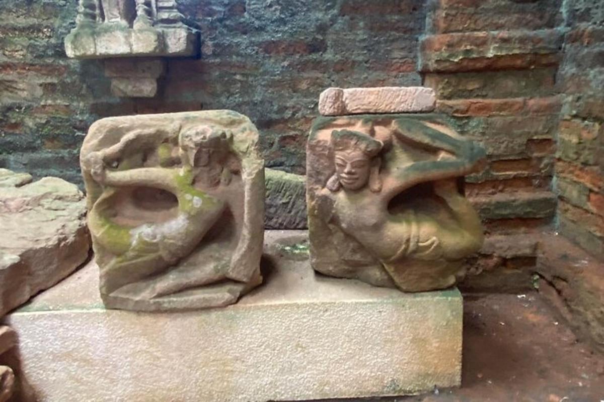 two stone statues sitting next to a brick wall