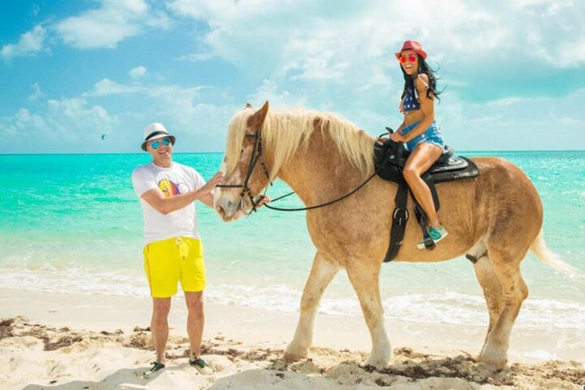a man and a woman riding a horse on the beach