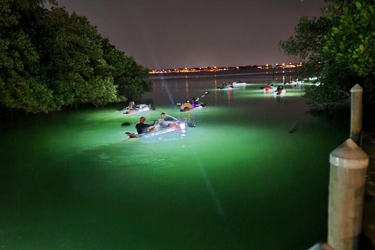 a group of people in boats in the water at night