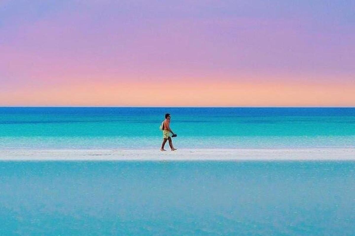 un uomo che cammina sulla spiaggia con un frisbee