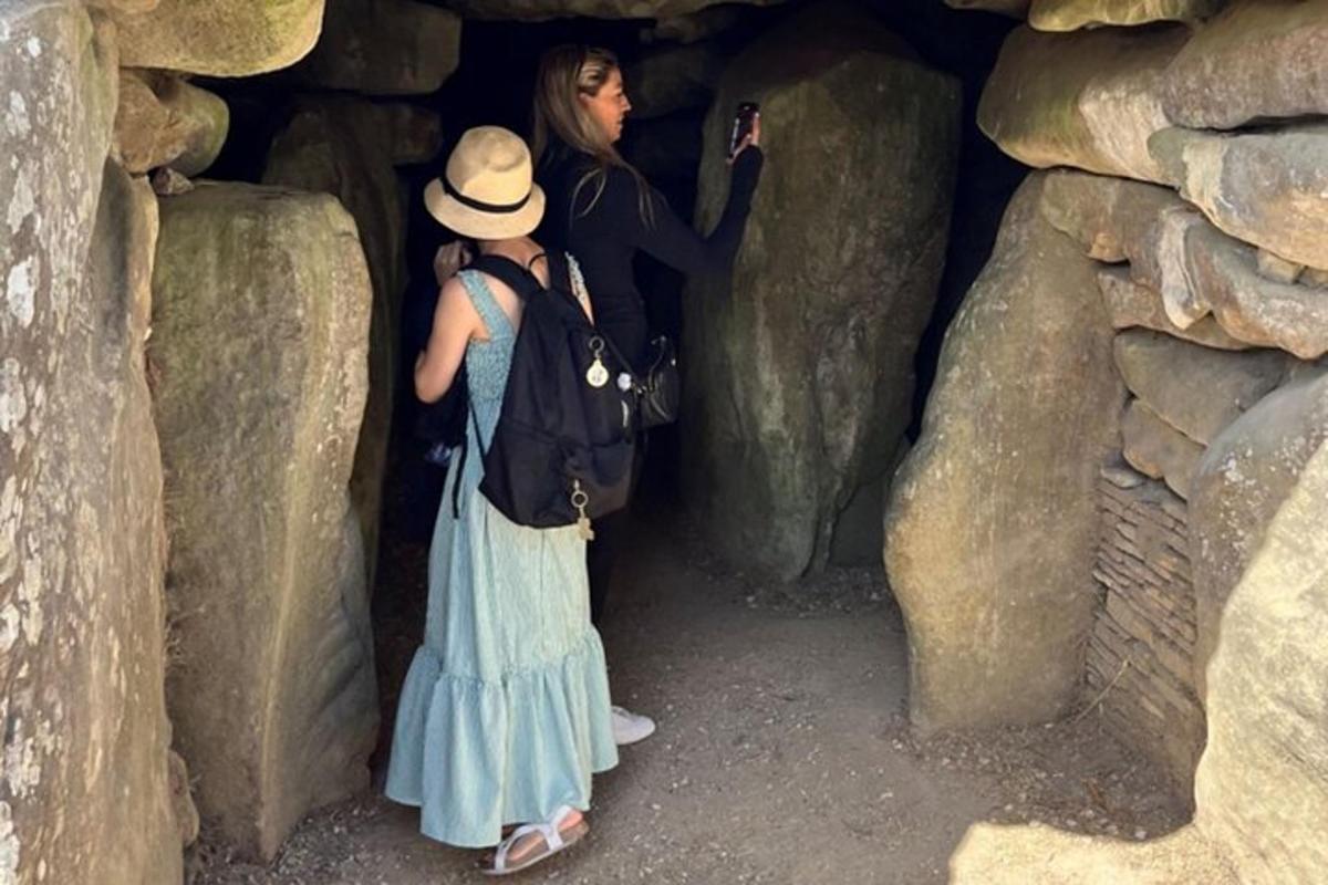 dues dones dretes en una cova amb un home fent-se una foto
