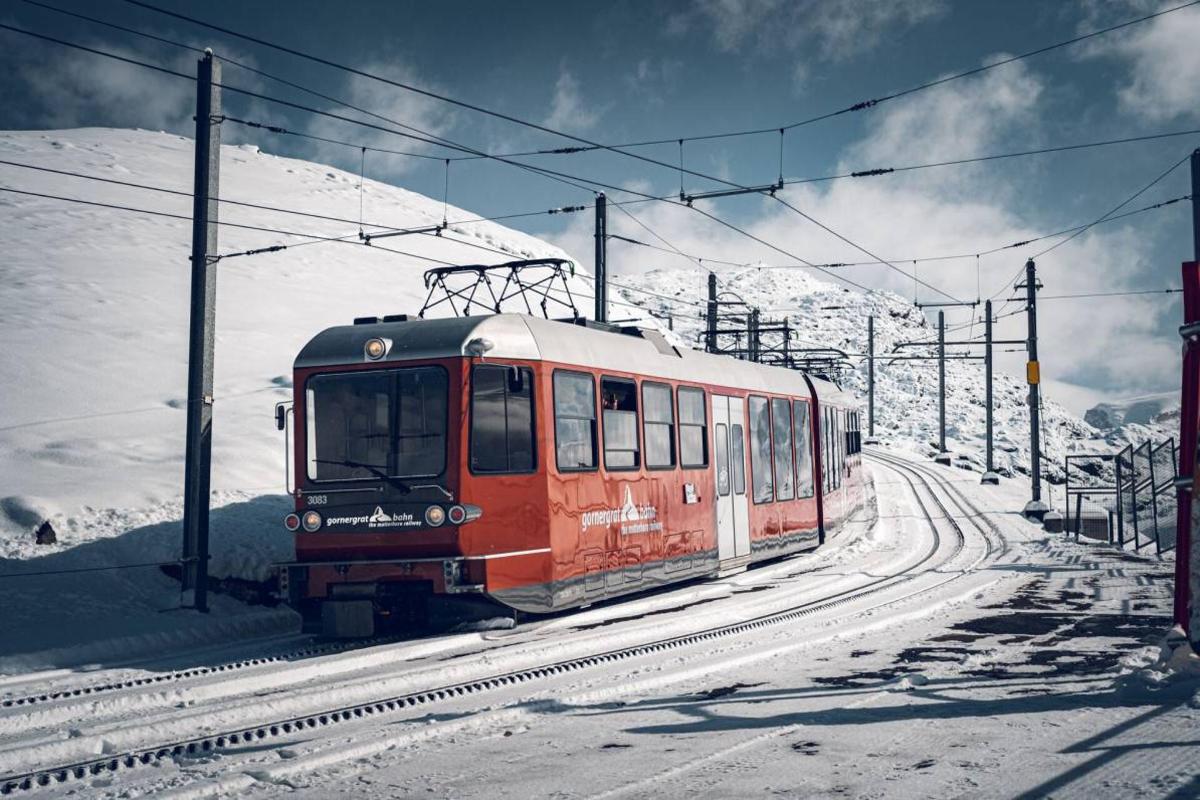 a red train on the tracks in the snow