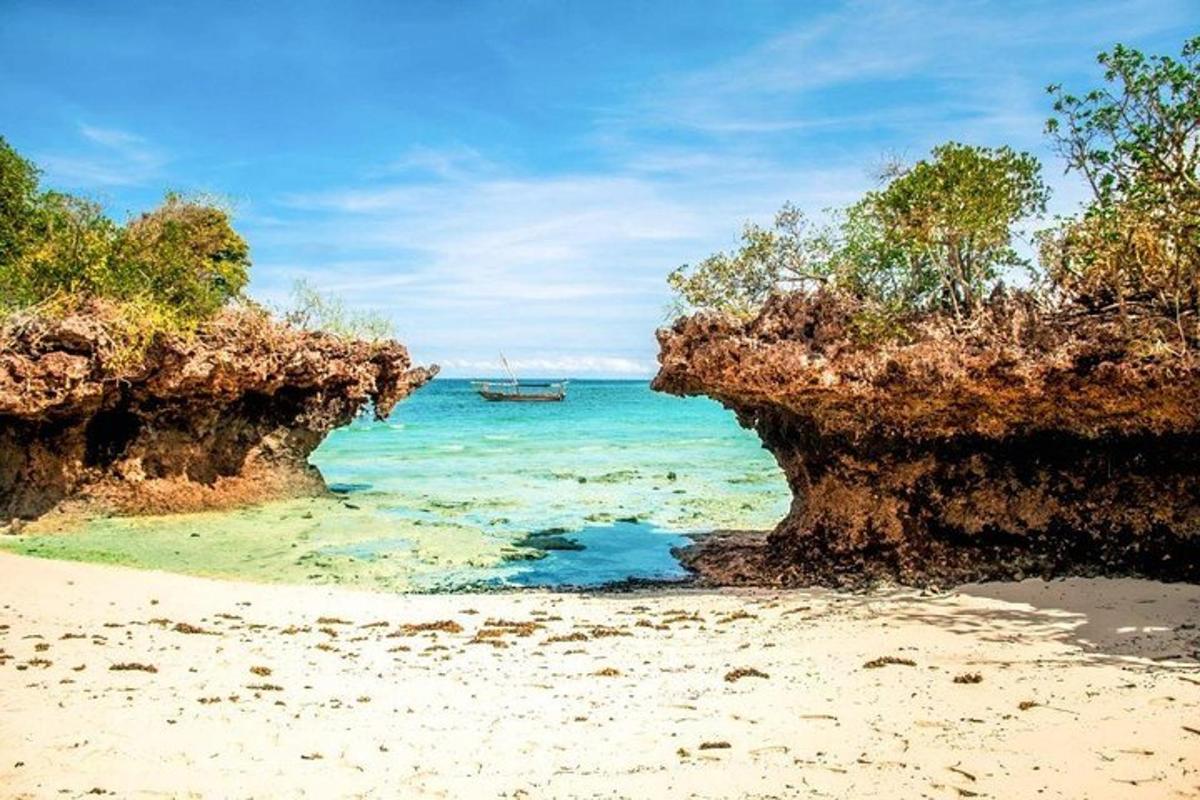 a beach with two cliffs and a boat in the water