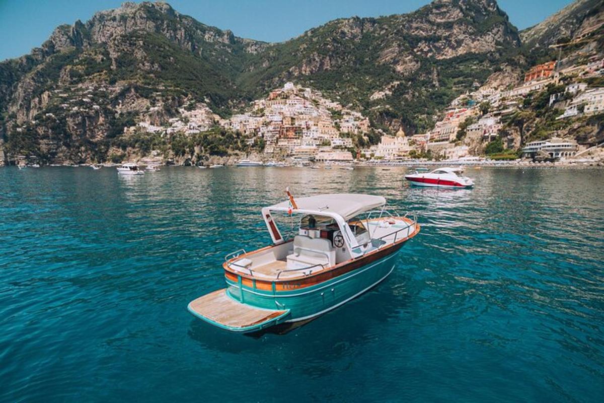 Un pequeño barco en el agua con montañas al fondo.