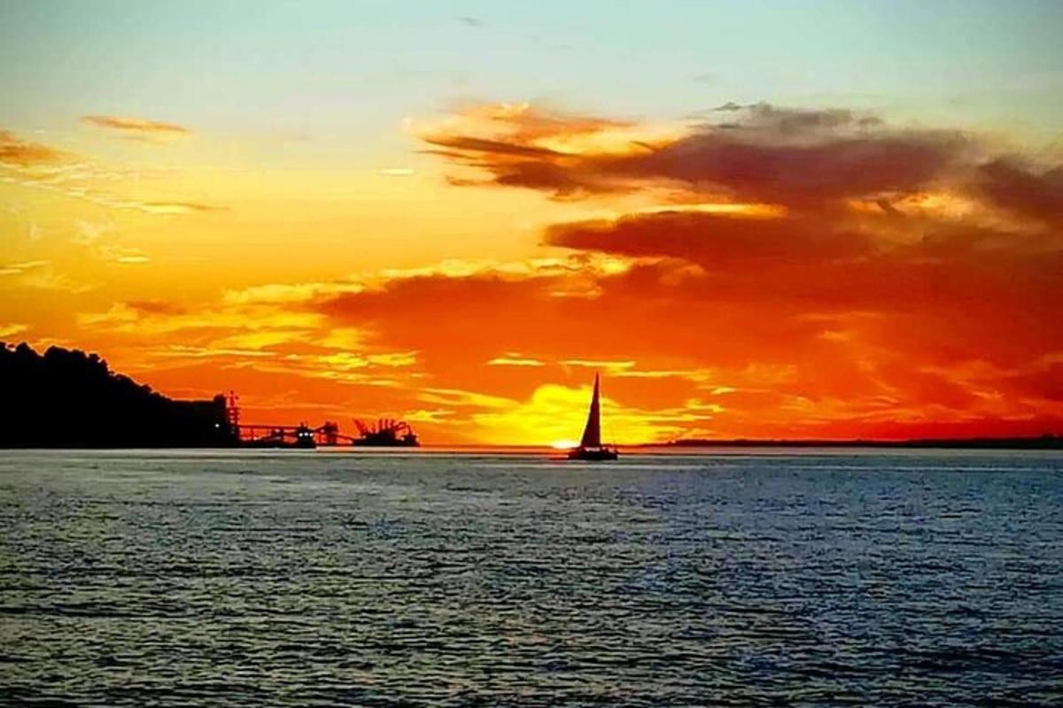una barca a vela sull'acqua con un tramonto