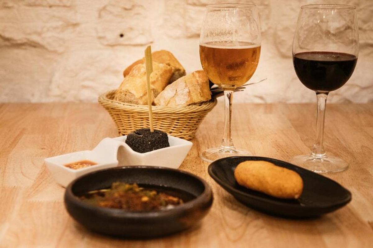 ένα τραπέζι με δύο ποτήρια κρασί και ένα πιάτο φαγητό και ψωμί