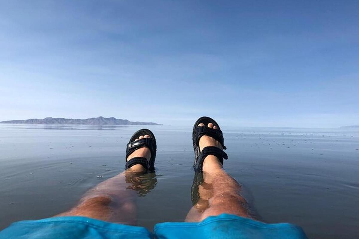 a man laying on the beach with his feet in the water