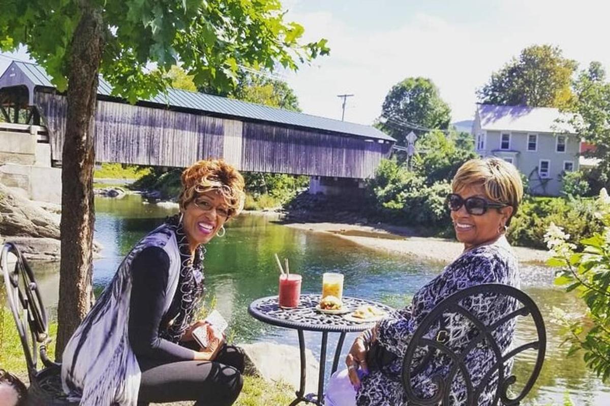 two women sitting at a table in front of a river