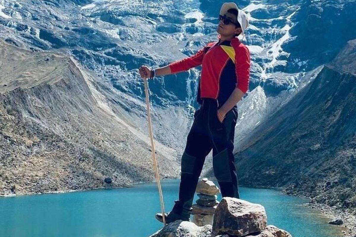 un uomo in piedi sulla cima di una montagna vicino a un lago