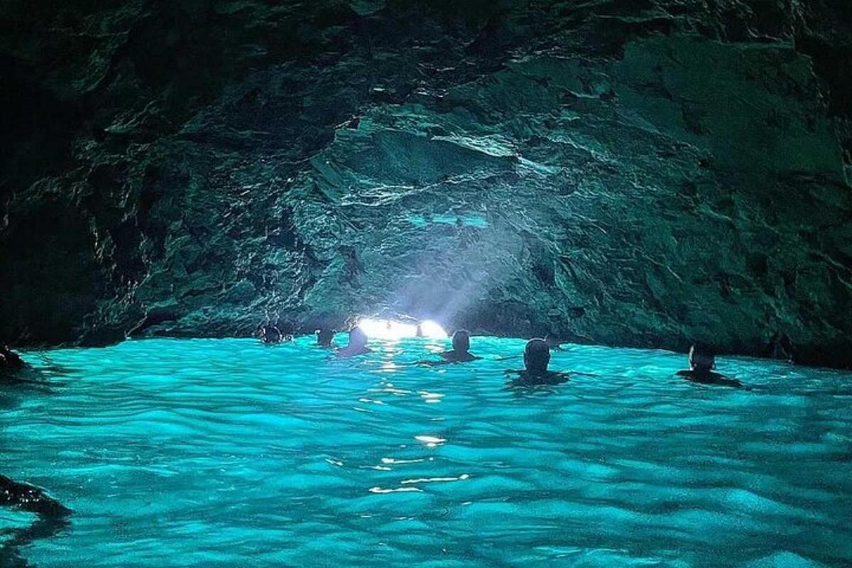 a group of people swimming in a blue cave