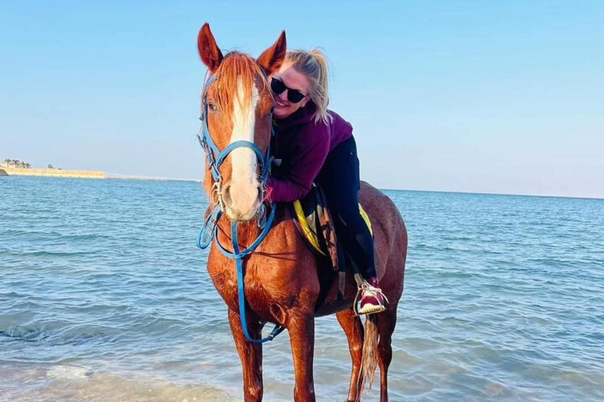 una dona muntant a cavall a la platja