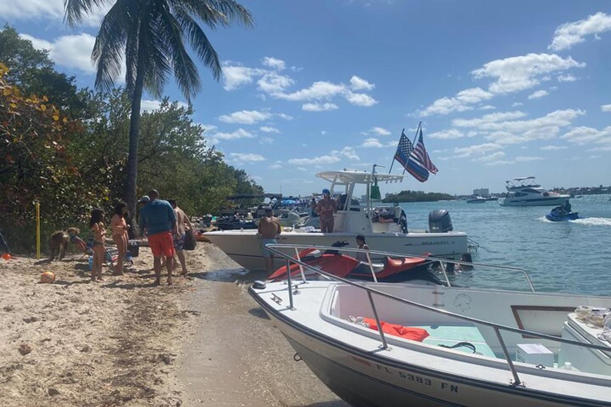 Un grupo de personas de pie en una playa junto a barcos.