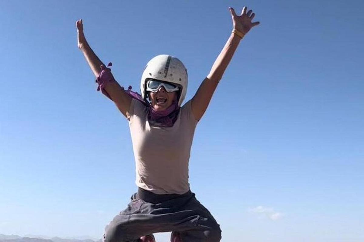 una donna che va sullo skateboard con le braccia alzate